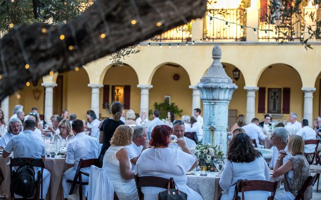 Diners all dressed in white seated a tables on a patio