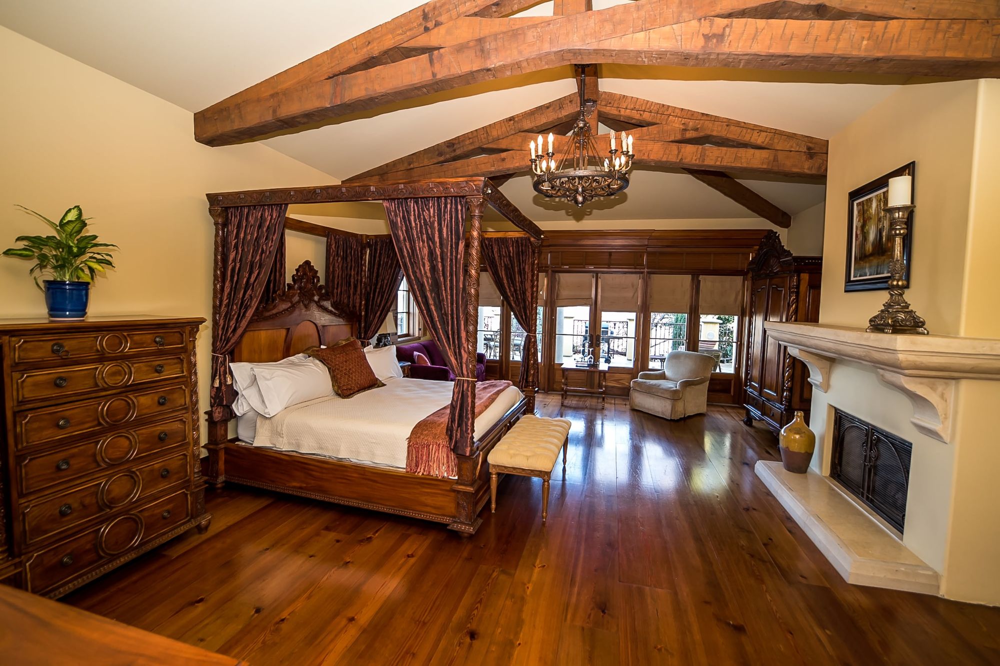 Wine-Makers-16-of-37_c7b8fab4541d950a91f126021f5e95da Big wooden rafters with canopy bed to the left and chest of drawers and decorative fireplace to the left